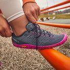 Barfußschuhe Merrell Vapor Glove 6 in Granite Fuchsia für Damen, getragen, erhältlich in unserem Onlineshop für Barfußschuhe. Flexibles Design und natürliches Laufgefühl für maximale Bewegungsfreiheit und Komfort bei jedem Schritt.